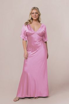 a woman in a pink dress posing for the camera with her hands on her hips