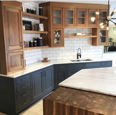 a kitchen with wooden cabinets and marble counter tops on the island in front of the sink