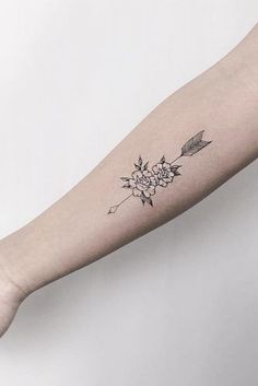 a woman's arm with a flower and arrow tattoo