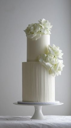 a three tiered cake with white flowers on top