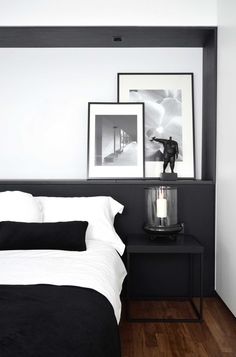 a black and white bedroom with pictures on the wall above the bed, along with candles