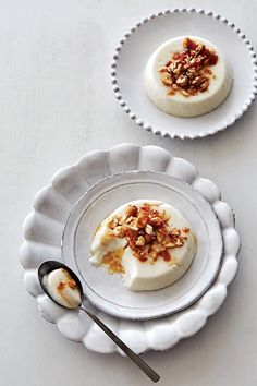 a white plate topped with food next to a bowl filled with fruit and nuts on top of a table