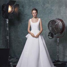 a woman standing in front of a camera wearing a white dress