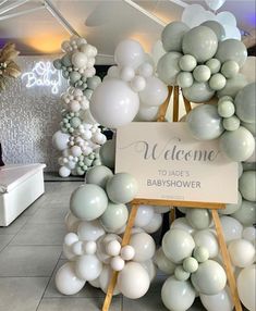 a welcome sign is surrounded by balloons in the shape of trees and flowers for a baby's shower