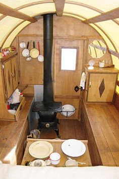 the interior of a small wooden cabin with a wood stove and various dishes on the table