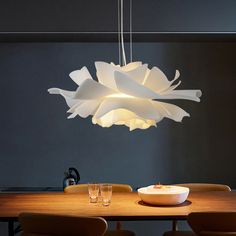 a light fixture hanging over a dining room table with chairs and bowls on the table