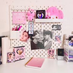 a white desk topped with lots of personal items and pictures next to a pink teddy bear