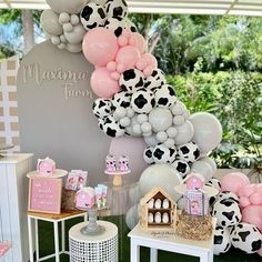 a table topped with lots of balloons next to a white and black cow print wall