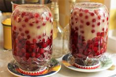 two jars filled with liquid and covered in pomegranates on top of a counter