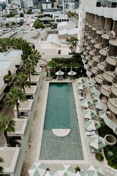 an aerial view of the pool and surrounding buildings with umbrellas in the foreground