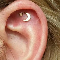 a woman's ear with a small crescent and star piercing