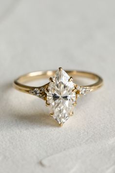 an engagement ring with three stones on the side and a diamond in the middle, sitting on a white surface