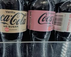 three bottles of coca - cola on display in a store