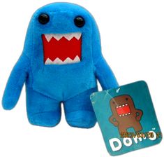 a blue stuffed animal with big teeth next to a small card board game called domo