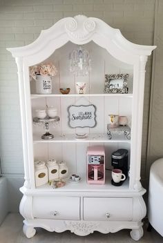 a white hutch with some items on top of it and a coffee maker next to it