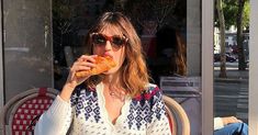 a woman sitting in a chair eating a doughnut