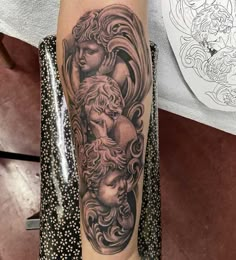 a woman's arm with an angel and cherub tattoo on the left forearm