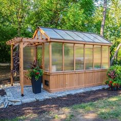 a small wooden greenhouse in the middle of some trees