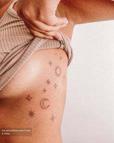 a woman's stomach with stars and moon tattoos on it, as well as her arm