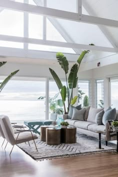 a living room filled with lots of furniture and large windows overlooking the ocean in front of it