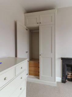 an empty room with white cabinets and drawers on the wall, next to a fireplace