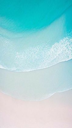 an aerial view of the beach and ocean with white sand, blue water and waves