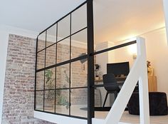 a room with a brick wall and white stairs leading up to the second floor area