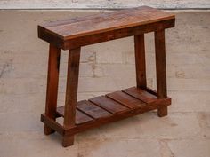 a small wooden table sitting on top of a stone floor next to a brick wall