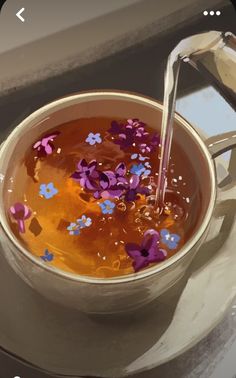 a tea pot filled with water and purple flowers floating in it, being poured from a metal faucet