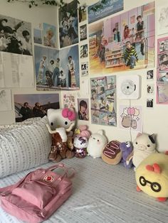 there are many stuffed animals sitting on the bed in this room with pictures all over the wall