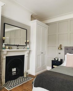 a bedroom with a bed, fireplace and mirror