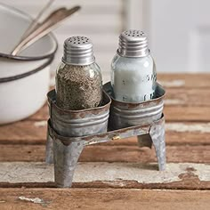 two salt and pepper shakers sitting on top of a wooden table