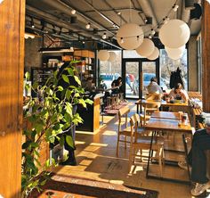 people sitting at tables in a restaurant with lots of light bulbs hanging from the ceiling