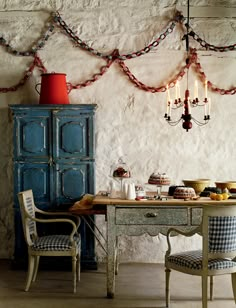 a dining room with a table and chairs next to a blue cabinet filled with food