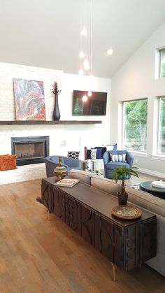 a living room filled with furniture and a fire place in front of a window on top of a hard wood floor