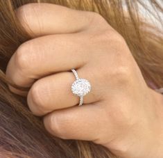 a woman's hand with a diamond ring on her left side and the middle finger