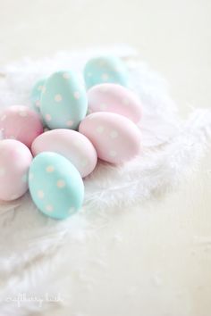 some pastel colored eggs are laying on a white furnishing area with polka dots