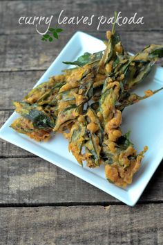 some food is on a white plate with green leaves in it and the words curry leaves pakoda