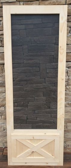 a wooden frame sitting on top of a table next to a stone wall and window