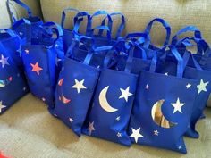 blue bags with stars and moon painted on them sitting on a couch in front of a pillow