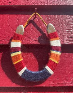 a knitted wreath hanging on the side of a red door