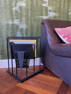 a brown leather couch sitting next to a table with two pieces of luggage on it