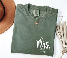 a t - shirt with the word mrs on it next to some feathers and a hat