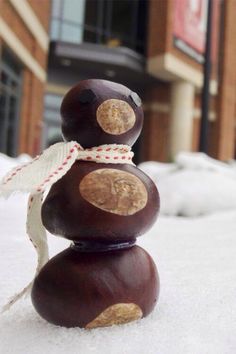 a snowman made out of rocks sitting in the middle of some snow outside a building