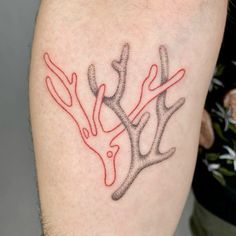 a tattoo on the arm of a man with red ink and two deer antlers