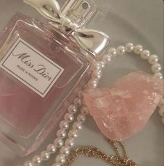 a bottle of perfume sitting on top of a table next to pearls and a necklace