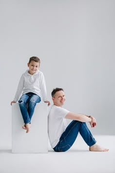 a man sitting on top of a white box next to a little boy