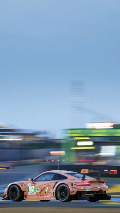 a car driving on a race track with blurry buildings in the background