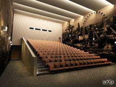 an empty auditorium with rows of seats in front of a large screen and roller coasters on the wall