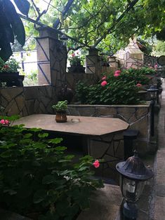 an outdoor table with potted plants on it and a lamp in the middle next to it